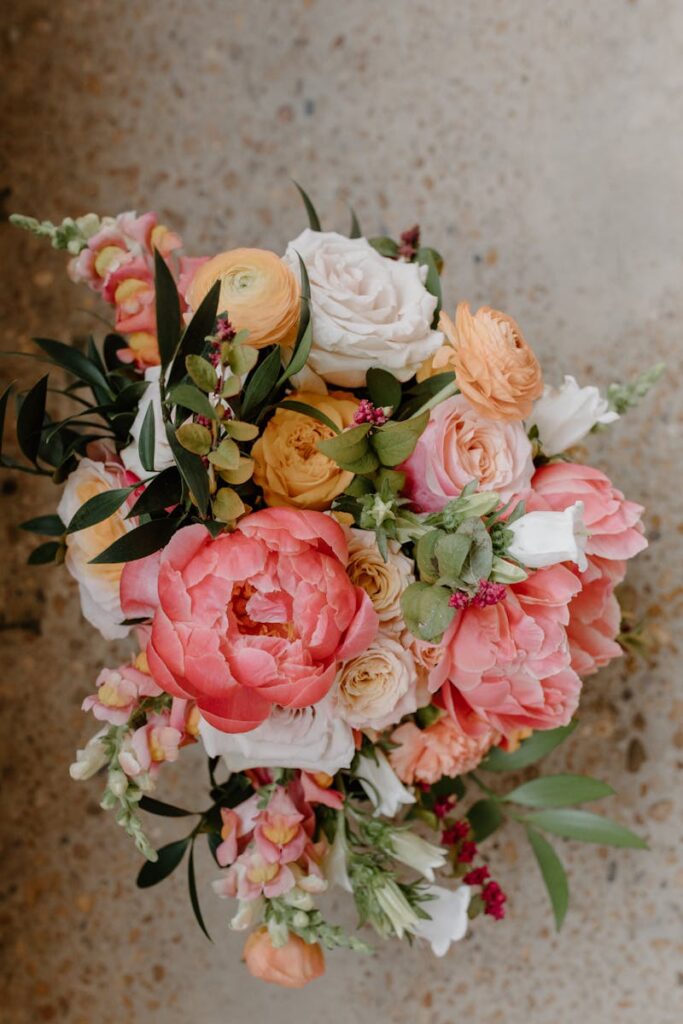 A stunning bridal bouquet featuring peonies, roses, and greenery in soft pastel colors.